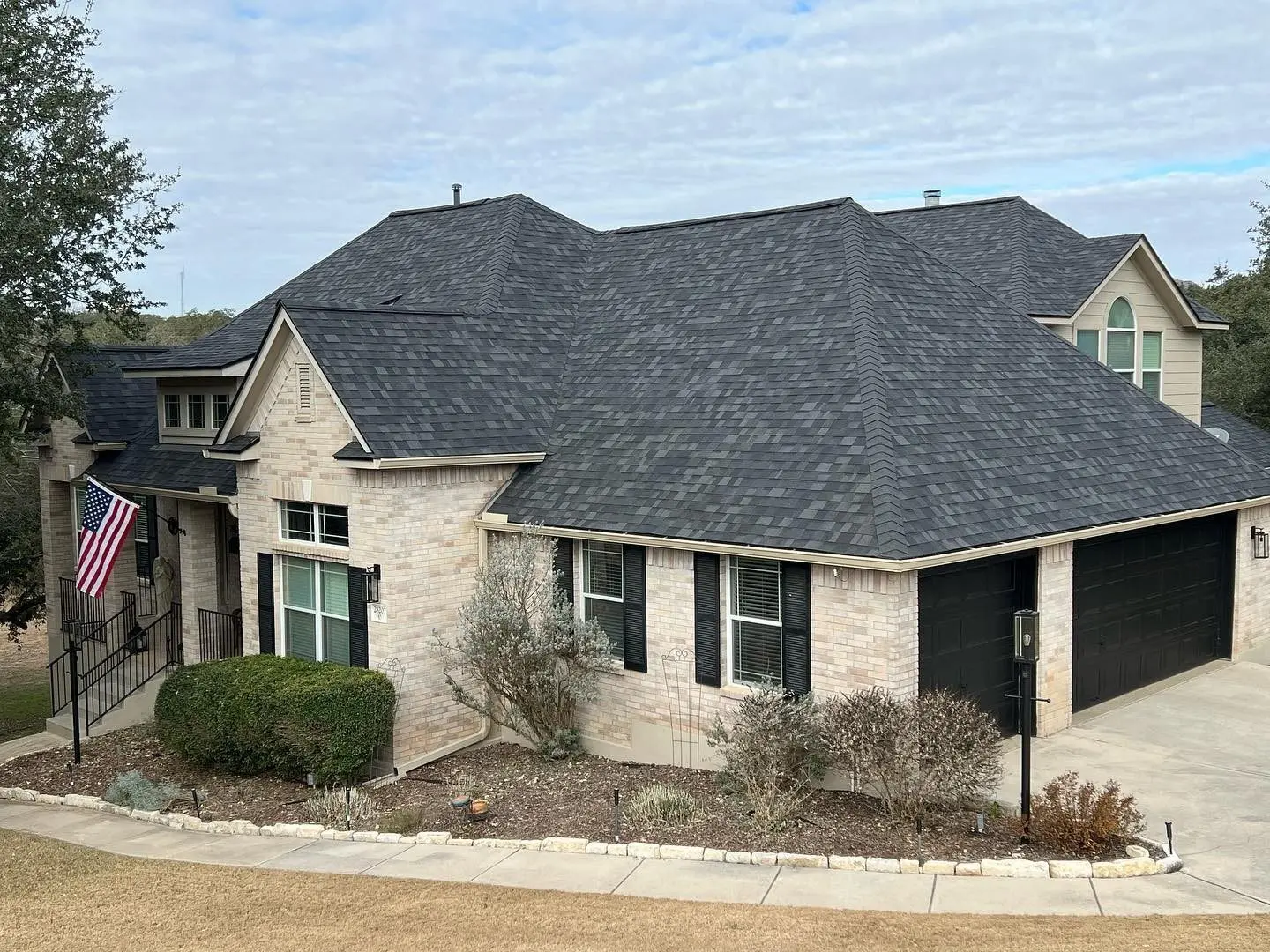 Completed Atrium Roofing shingle roof replacement on a San Antonio home flying the American flag