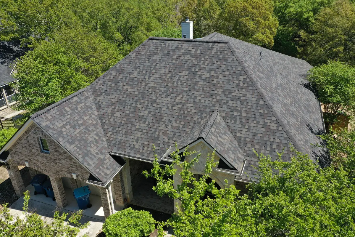 Aerial view of a house with a black laminated shingle roof and multiple gables.