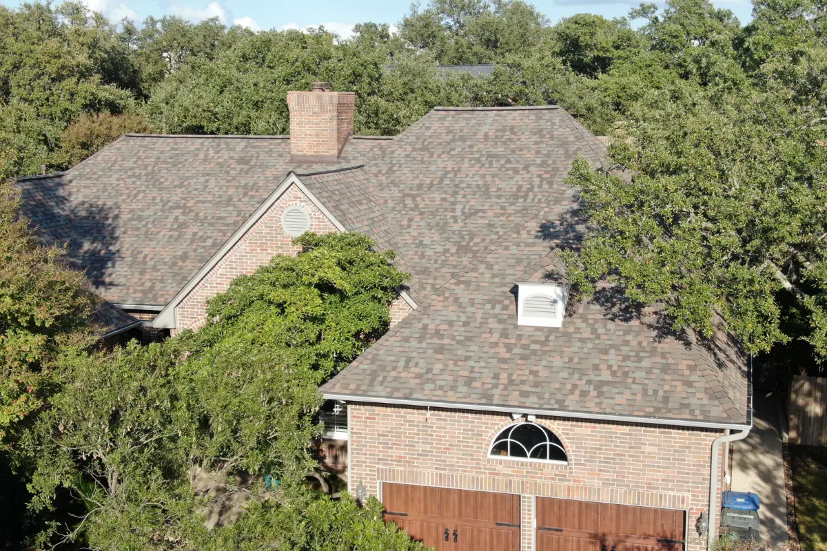 Aerial view of a brick home finished with a copper-toned laminated shingle roof.