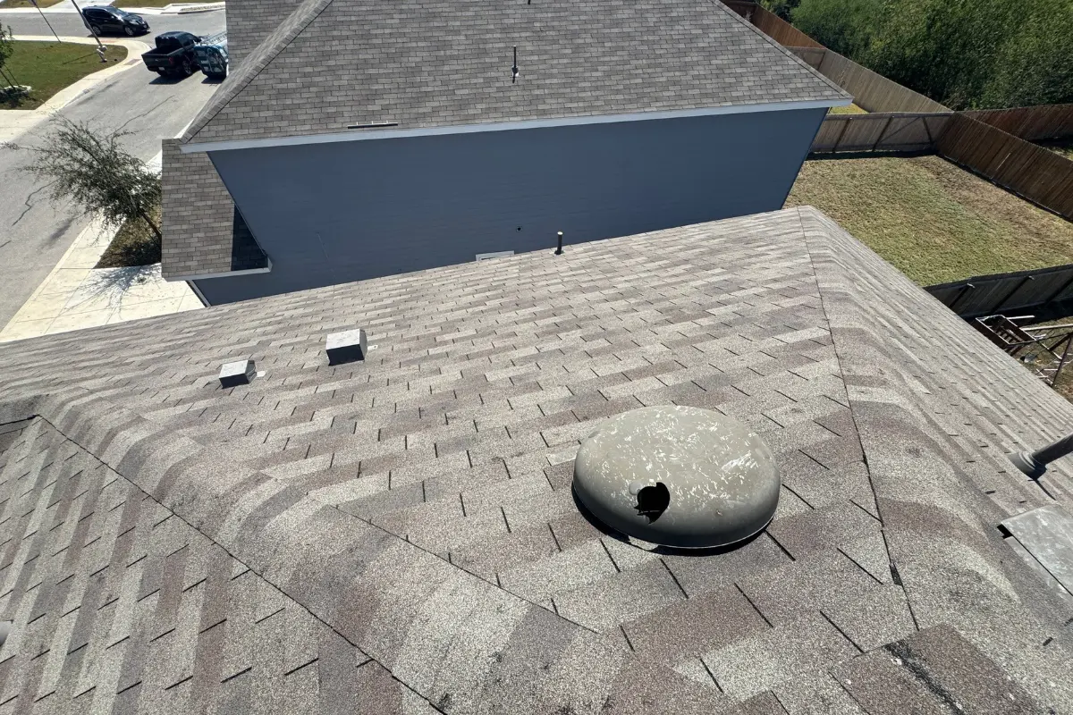 The punctured roof vent seen in context from roof level among asphalt shingles on Kellog Court in Converse