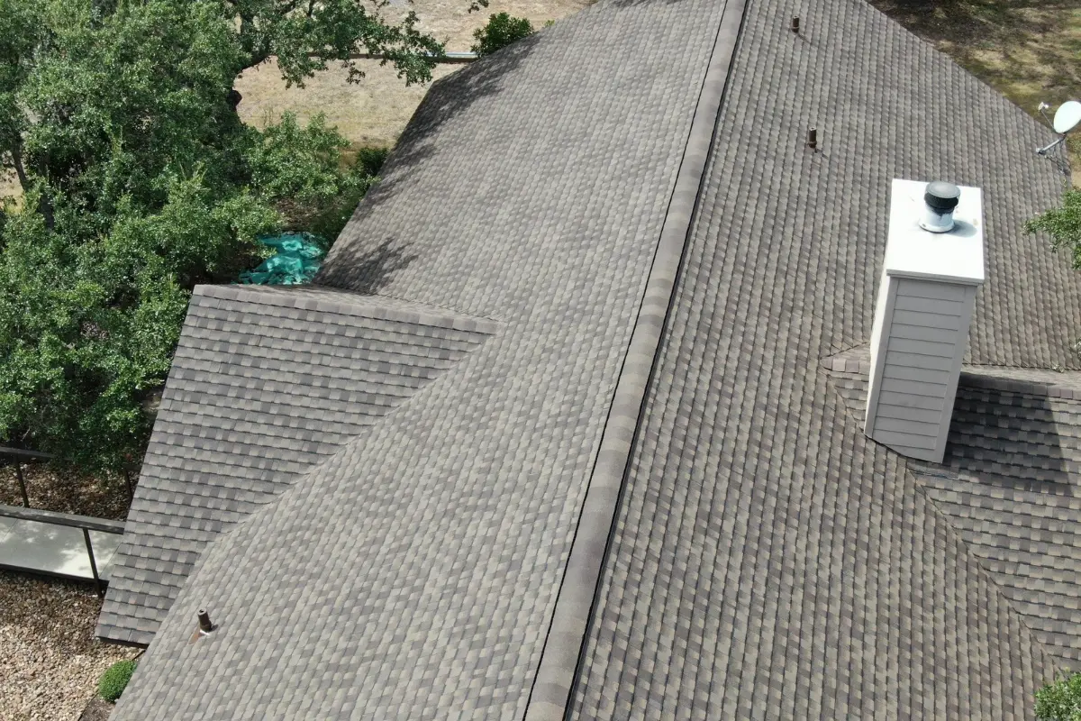 Aerial view of a completed IMPACTSHIELD roof showing the chimney and ridge in Bergheim, TX