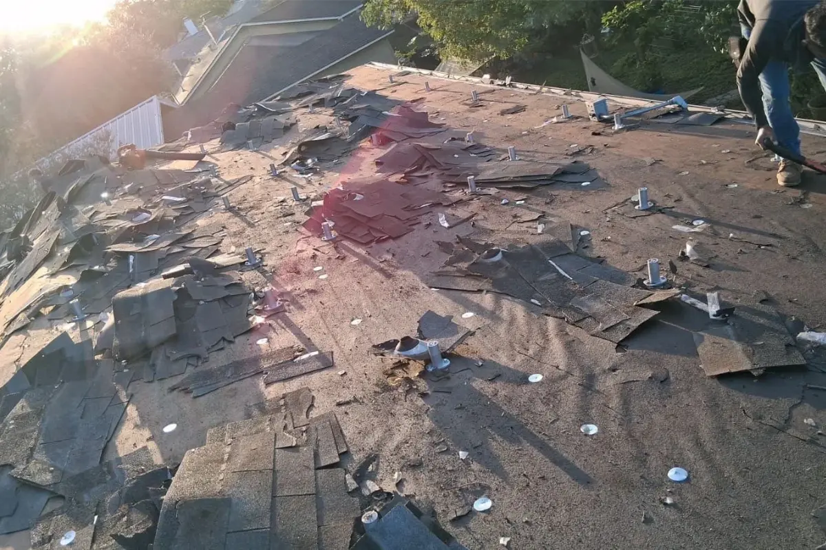 Crew tearing off old shingles during roof demolition in San Antonio