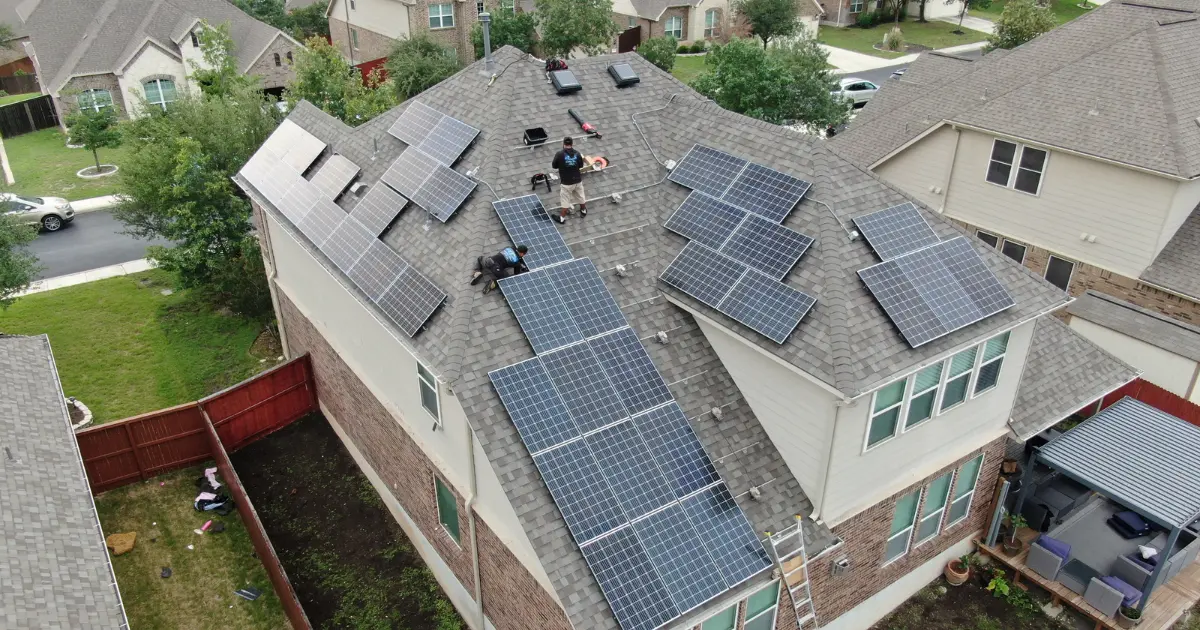 Aerial view of a multi-level house with a new shingle roof and the solar array back in place.